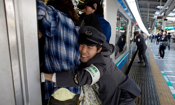 Một nhân viên hỗ trợ đẩy hành khách vào toa tàu ở Tokyo